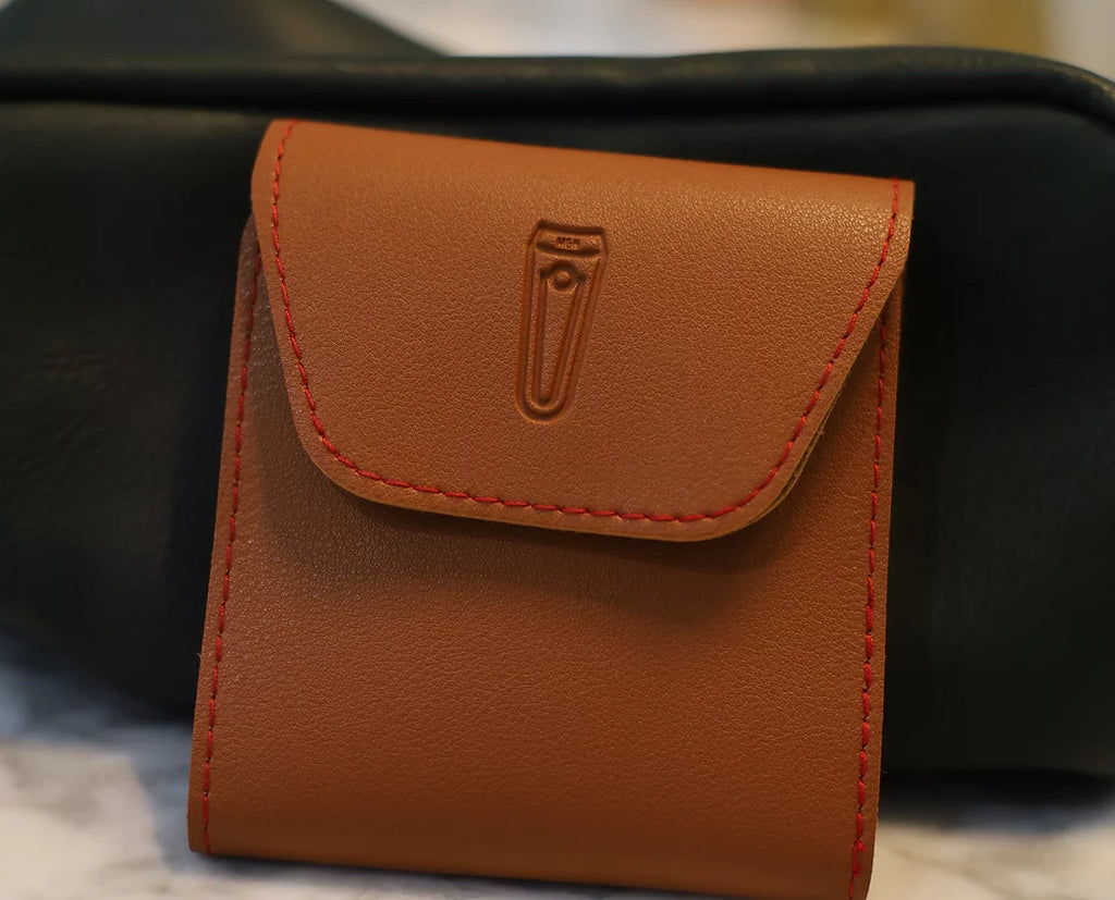 A collection of nail grooming tools including nail clippers, file, scissors, tweezers, cuticle pusher, and other items, neatly arranged in an open brown case.
